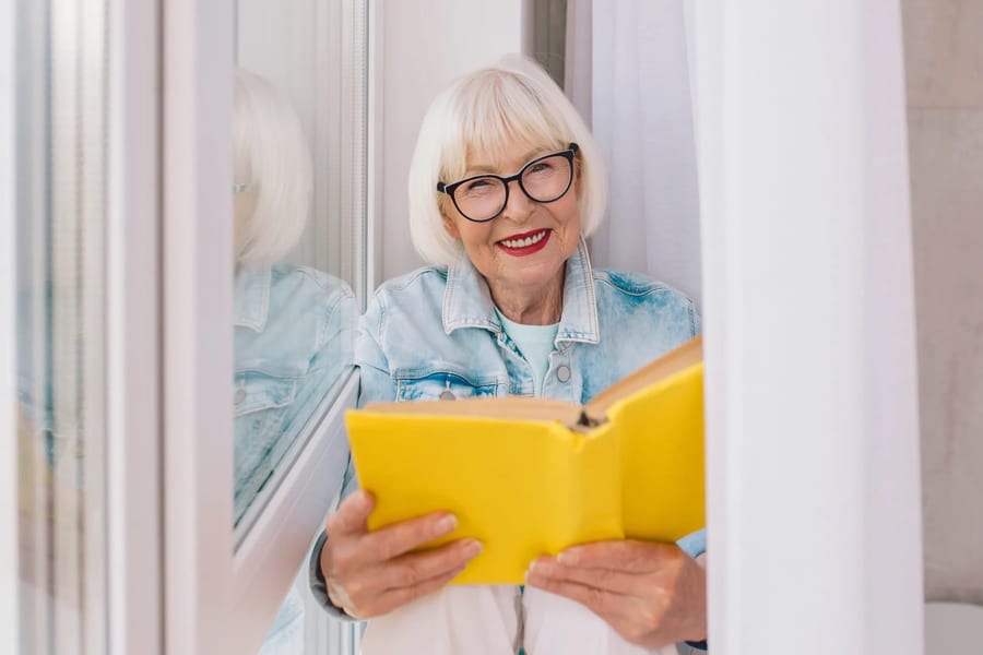 Senior woman reading peacefully by a window at home